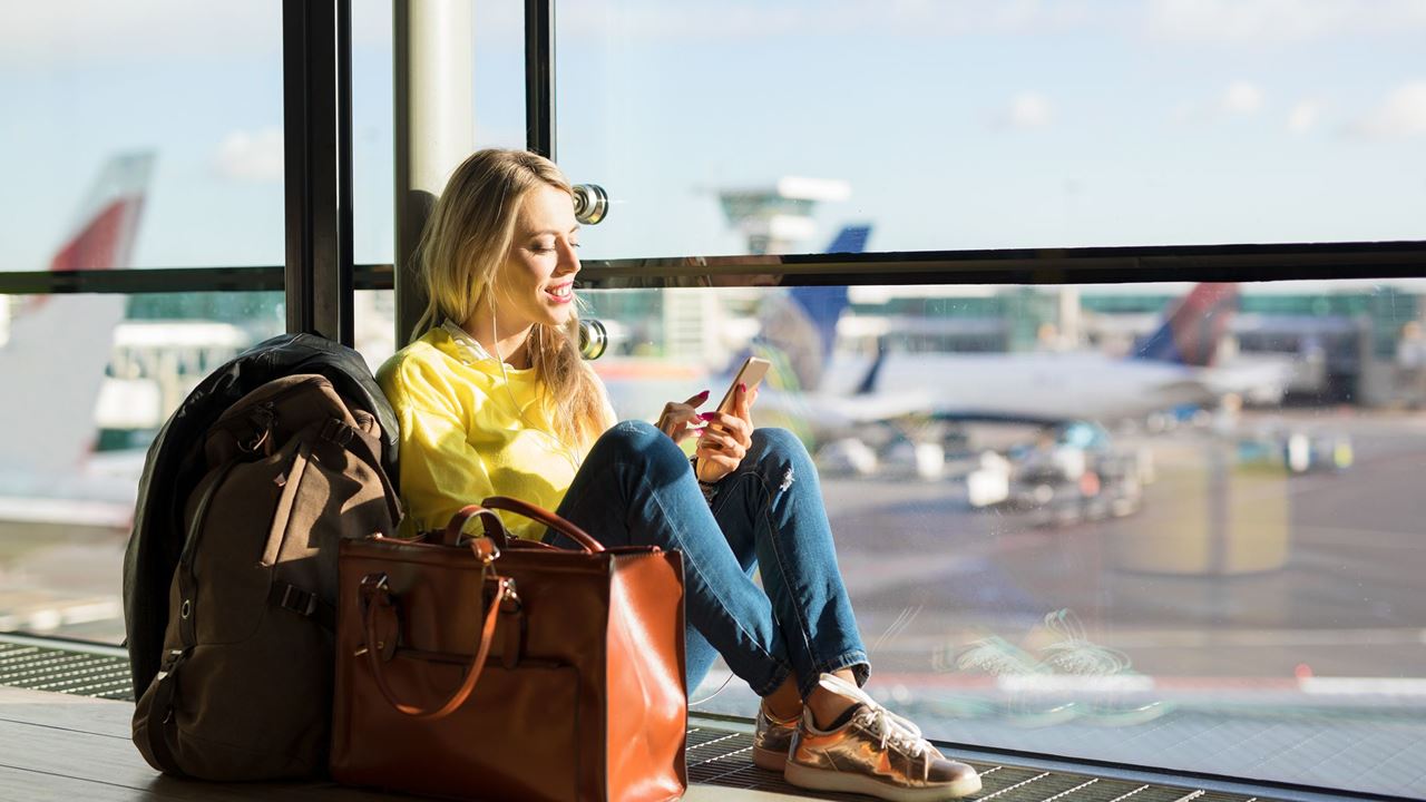 Smiling woman looking at phone at airport