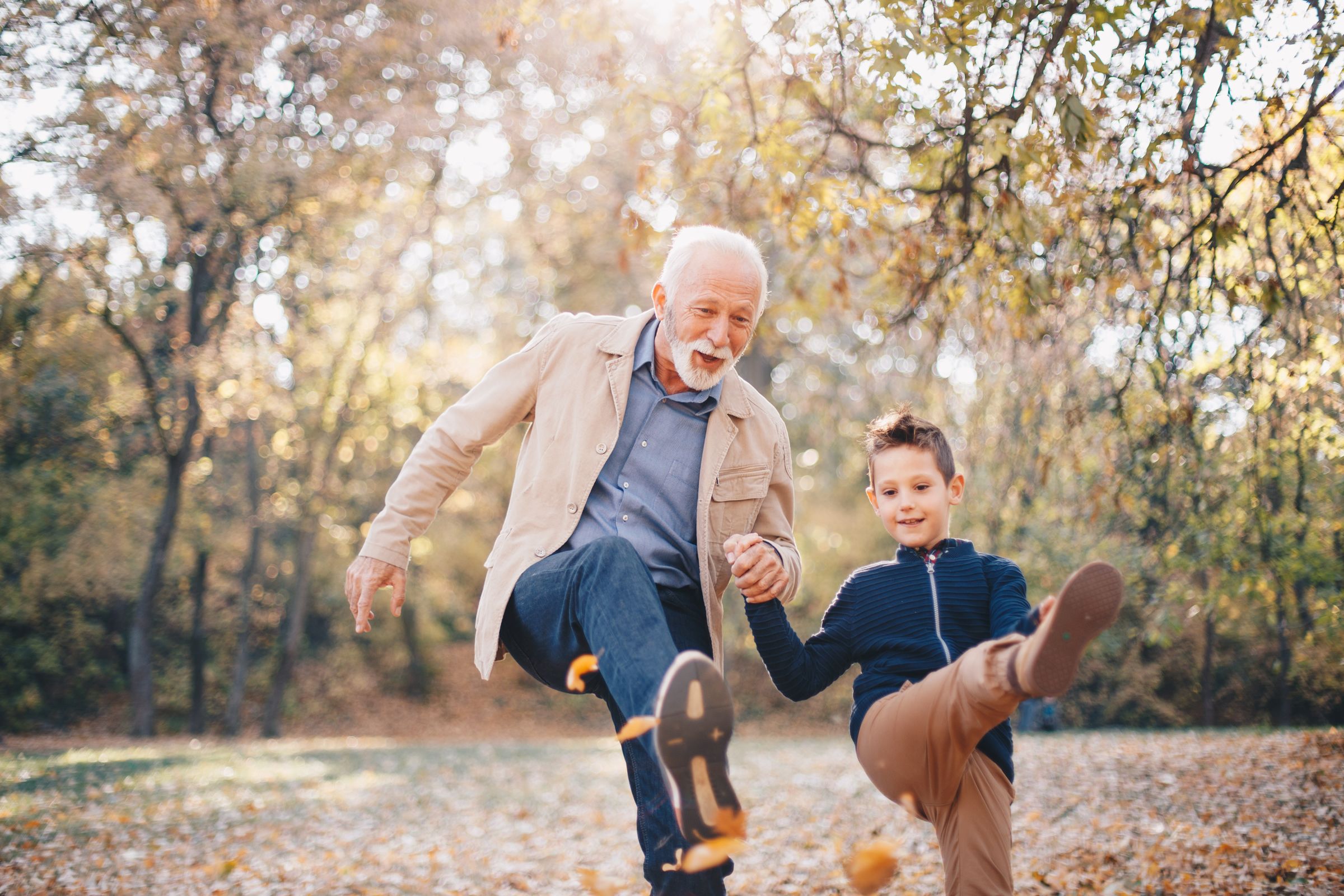 man and boy kicking leaves