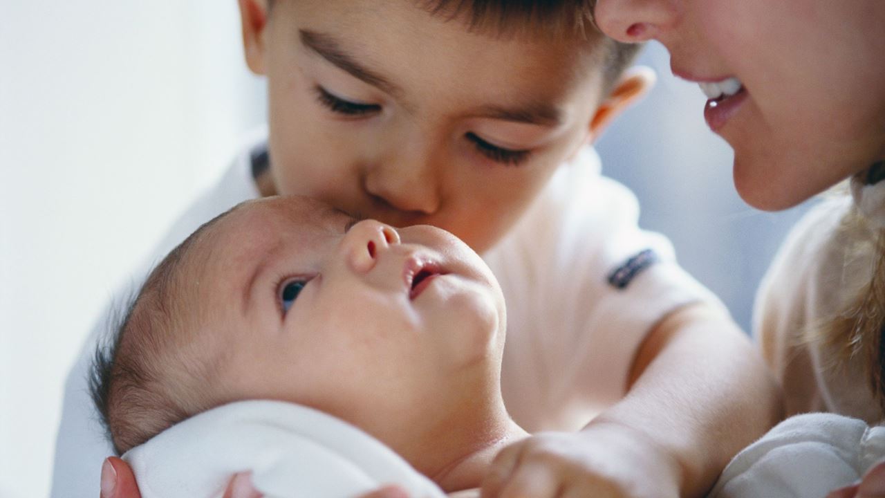 New born baby being kissed by brother